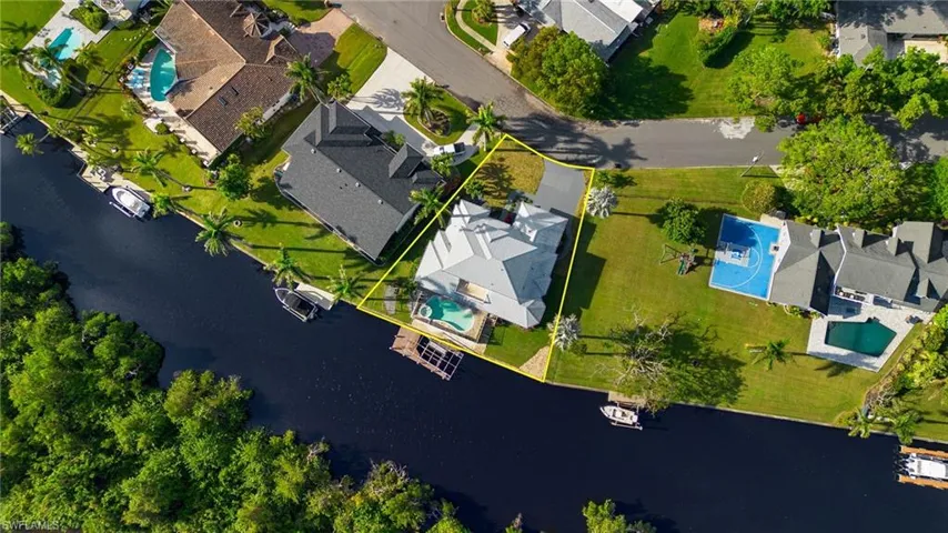 Aerial view of residential area with a large body of water and property parcel outlined