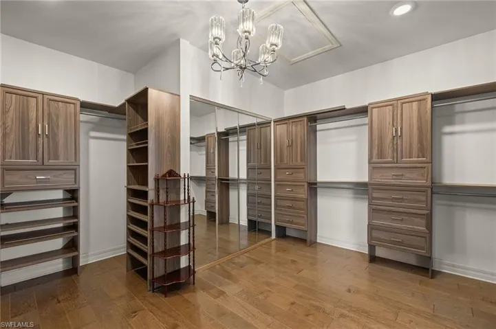 Walk in closet featuring dark wood-style floors and a chandelier