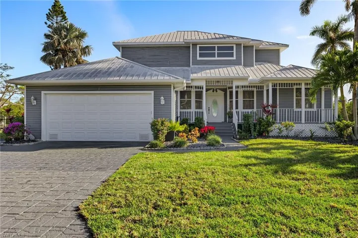 View of front facade featuring covered porch, a metal roof, decorative driveway, a garage, and a front yard