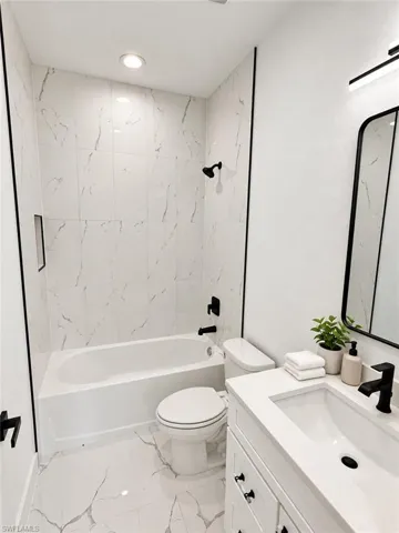 Tub/shower combination featuring white tile surround with dark veining