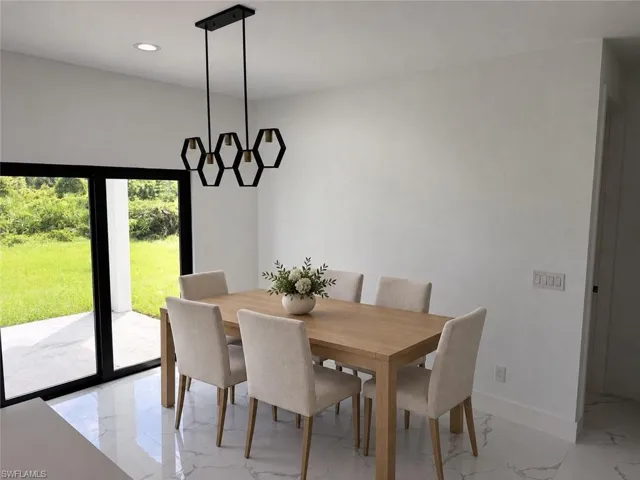 Recessed ceiling lighting, modern linear chandelier, sliding glass doors, white tile flooring, and a patio area