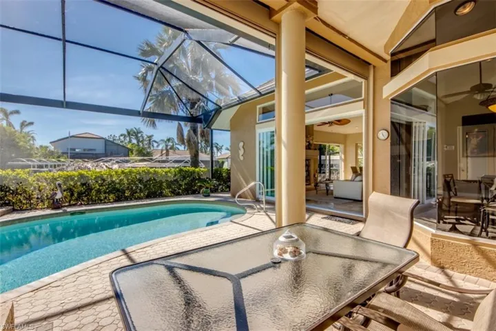 View of swimming pool featuring a patio, glass enclosure, and ceiling fan