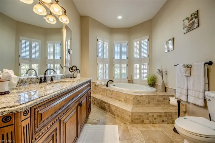 Bathroom with vanity, a relaxing tiled tub, and toilet