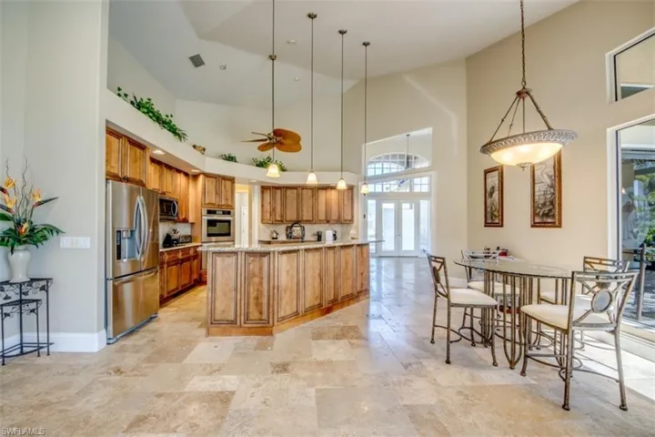 Kitchen with hanging light fixtures, ceiling fan, stainless steel appliances, and a high ceiling