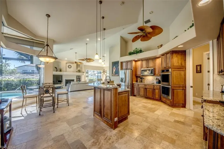 Kitchen featuring light stone countertops, hanging light fixtures, ceiling fan, and stainless steel appliances