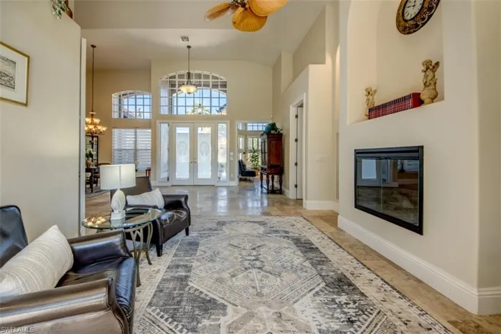 Living room featuring french doors and ceiling fan with notable chandelier