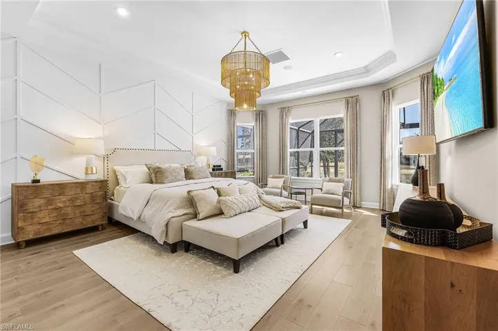 Bedroom featuring light wood-style flooring, hanging lights, and a raised ceiling