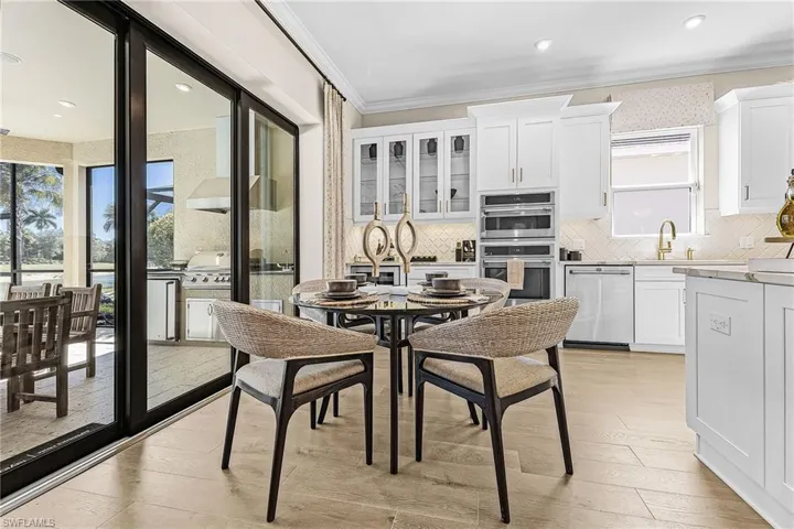 Kitchen featuring white cabinetry, stainless steel appliances, light wood finished floors, crown molding, and backsplash