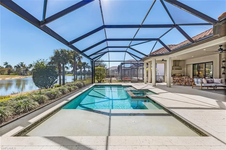 Relaxing pool / spa with a sunroom, a patio, glass enclosure, an outdoor hangout area, and a water view