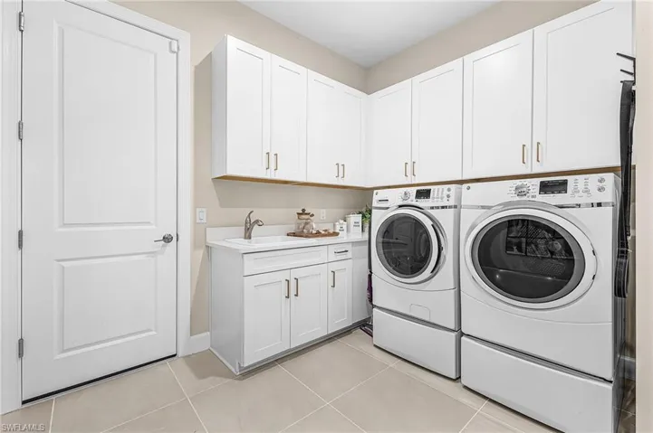 Laundry area featuring independent washer and dryer, light tile patterned flooring, and cabinet space