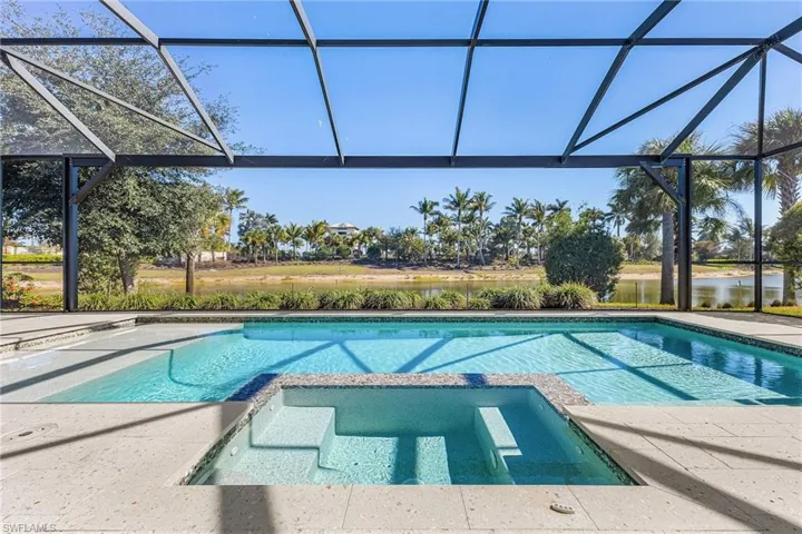 Integrated pool / spa with glass enclosure, a patio, and a water view
