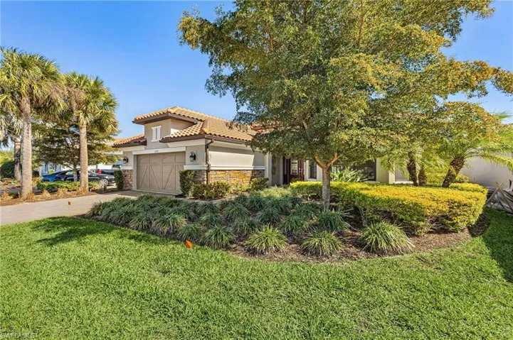 View of front of property featuring a front yard, stucco siding, driveway, stone siding, and an attached garage