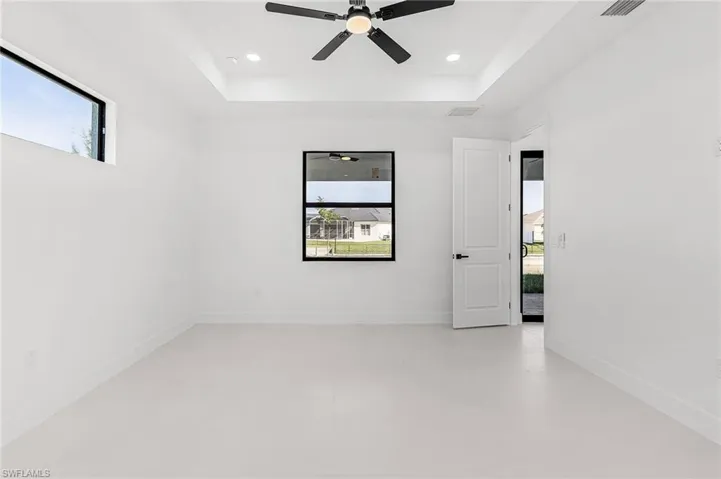 Primary Bedroom with fan and tray ceiling