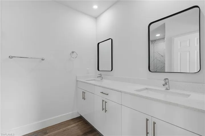 Full bath featuring double vanity, dark wood finished floors, and recessed lighting