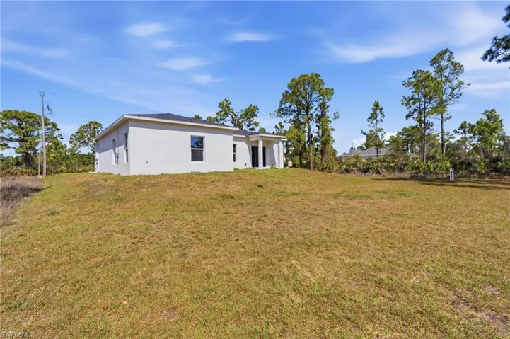 Rear view of property featuring a yard and stucco siding
