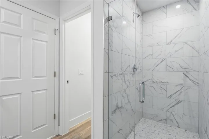 Full bathroom featuring a marble finish shower and light wood-type flooring