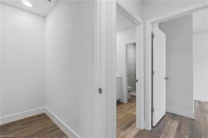 Hallway featuring dark wood-type flooring and baseboards
