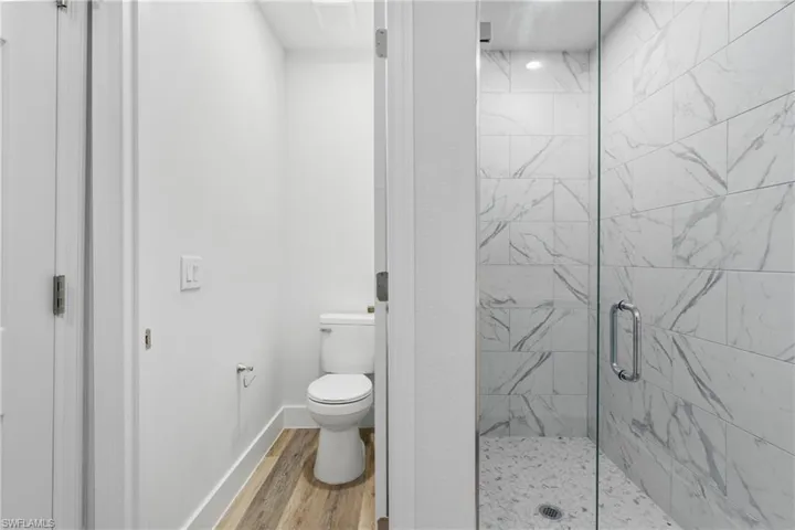 Bathroom featuring a marble finish shower and light wood-style flooring
