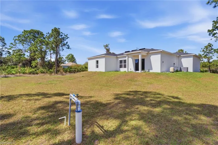 Rear view of property featuring a lawn and stucco siding