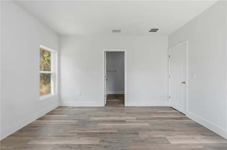 Unfurnished bedroom featuring a spacious closet and light wood-style flooring