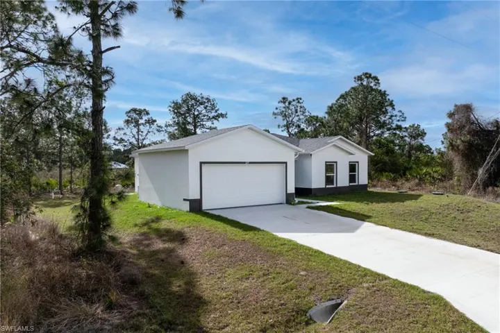 Ranch-style house with driveway, a garage, a front lawn, and stucco siding