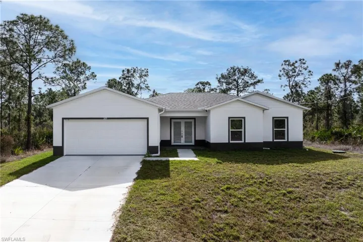 Ranch-style home featuring a front yard, french doors, concrete driveway, an attached garage, and stucco siding