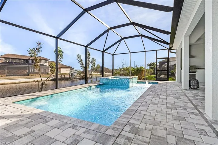 View of pool featuring a patio area, a lanai, an in ground hot tub, and a water view