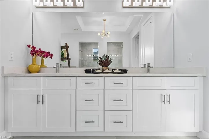 Bathroom with crown molding, a notable chandelier, a raised ceiling, vanity, and an enclosed shower