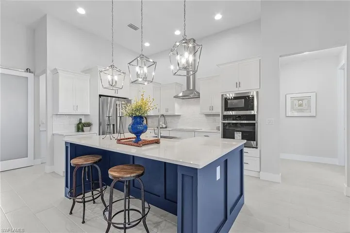 Kitchen with a spacious island, appliances with stainless steel finishes, pendant lighting, and white cabinets