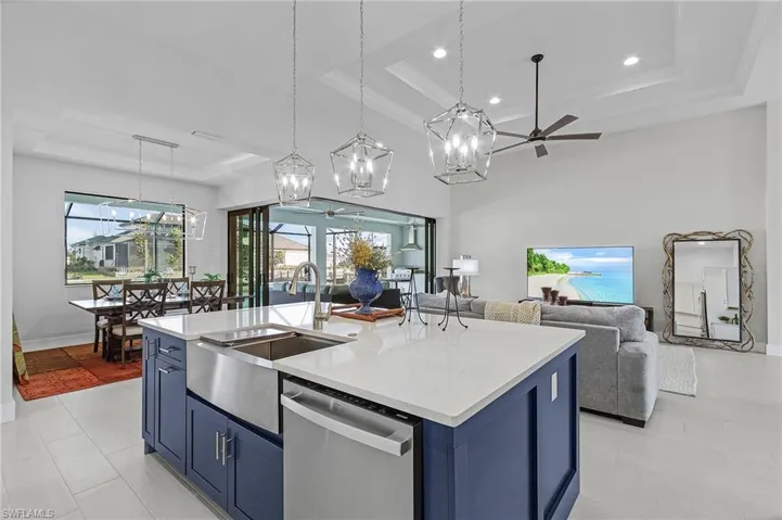 Kitchen featuring a healthy amount of sunlight, a kitchen island with sink, stainless steel dishwasher, and pendant lighting
