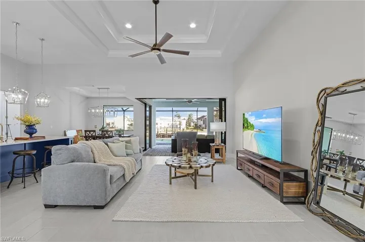 Living room featuring ceiling fan, a high ceiling, and a raised ceiling