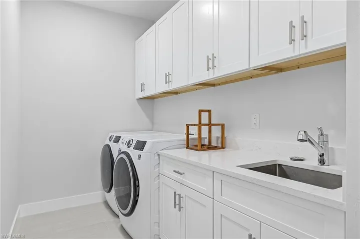 Laundry room featuring washing machine and dryer, cabinets, and sink