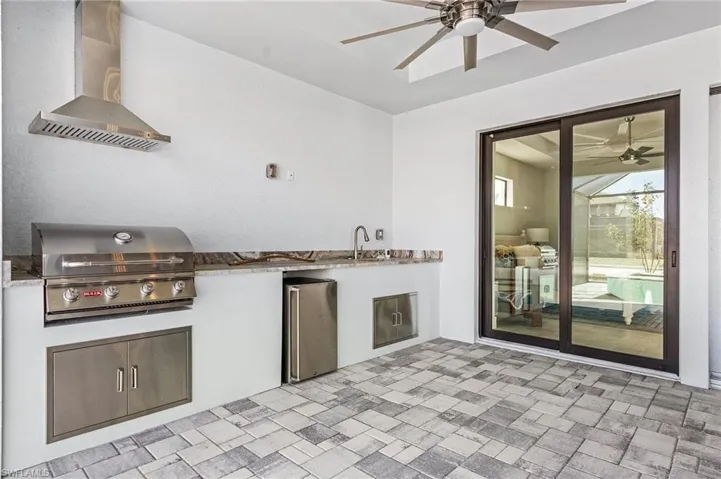 View of patio featuring area for grilling, ceiling fan, sink, and a grill