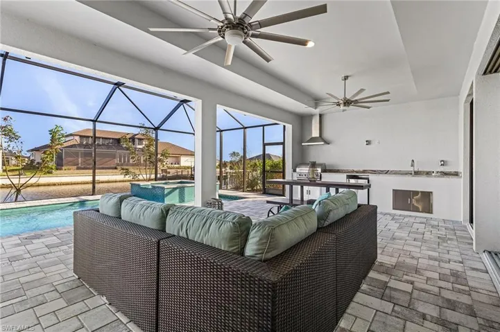 View of patio / terrace featuring a lanai, grilling area, ceiling fan, outdoor lounge area, and a swimming pool with hot tub