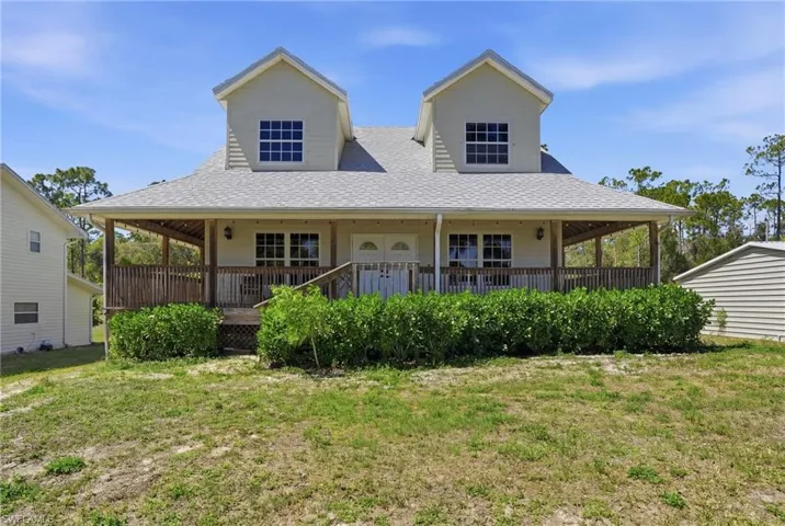 Farmhouse inspired home featuring covered porch, a front yard, and roof with shingles