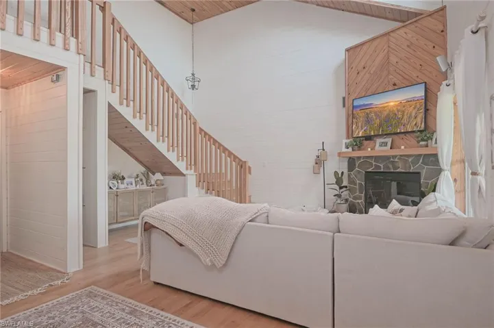 Living area featuring wood finished floors, a vaulted wood ceiling, a fireplace, and tongue and groove walls