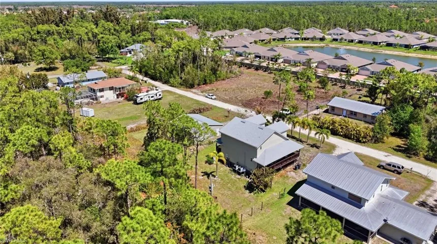 Aerial view of residential area featuring a mature woods and a large body of water