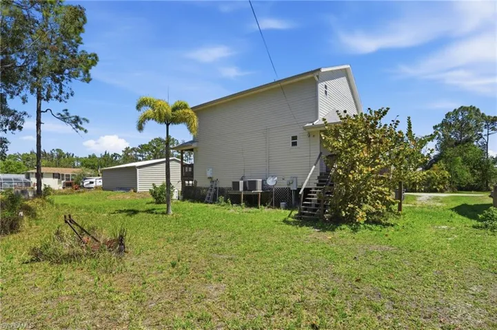 Back of house featuring a yard and stairway from the wrap around porch