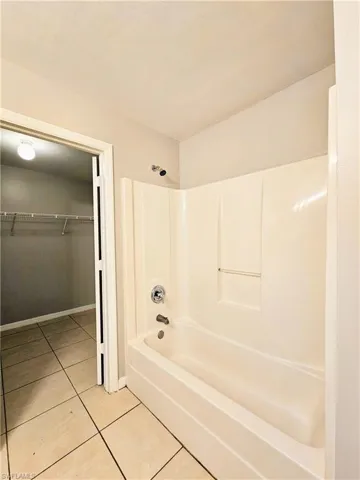 Full bathroom featuring tub / shower combination, light tile patterned flooring, and a spacious closet