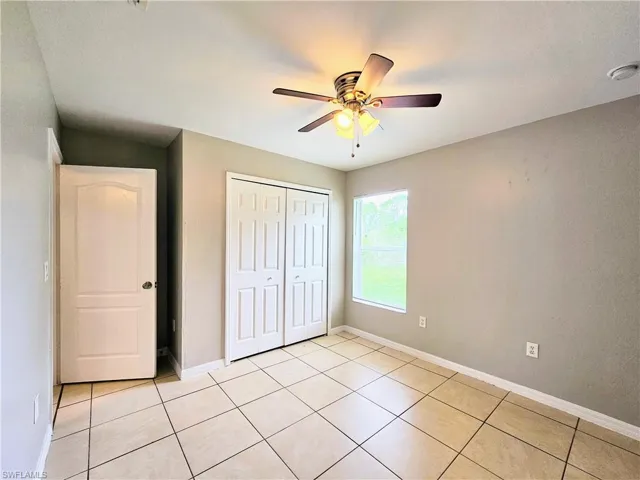 Unfurnished bedroom featuring light tile patterned flooring, ceiling fan, and a closet