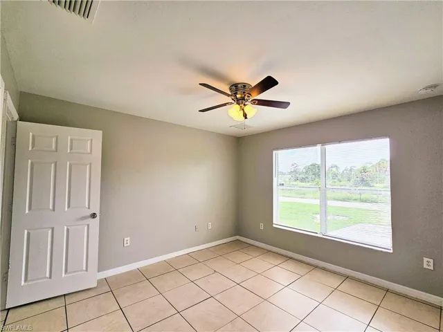 Unfurnished room with light tile patterned floors and a ceiling fan