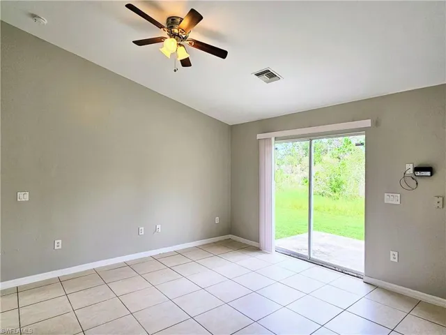 Empty room featuring light tile patterned flooring and ceiling fan