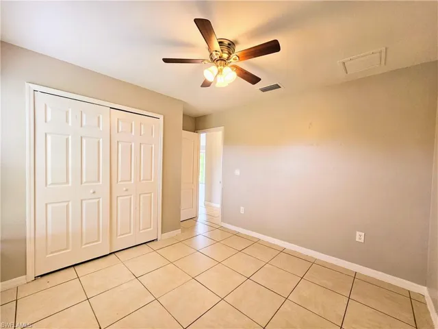Unfurnished bedroom featuring light tile patterned floors, a closet, and ceiling fan