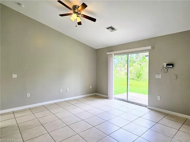 Empty room featuring light tile patterned floors, a ceiling fan, and vaulted ceiling