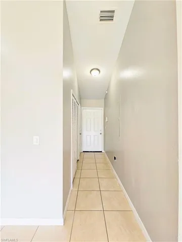 Hallway featuring light tile patterned floors and baseboards