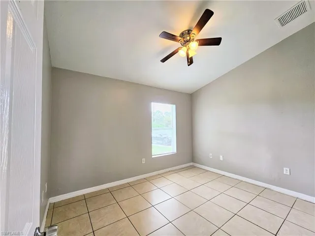 Empty room featuring vaulted ceiling, light tile patterned floors, and ceiling fan