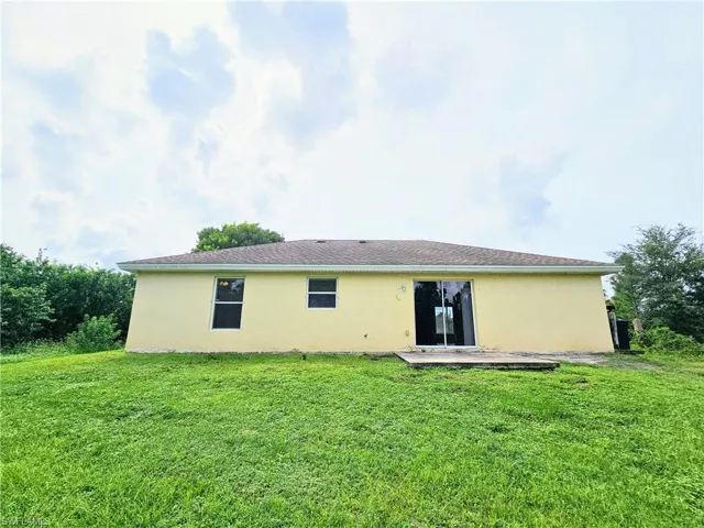 Back of house with stucco siding, a yard, and a patio