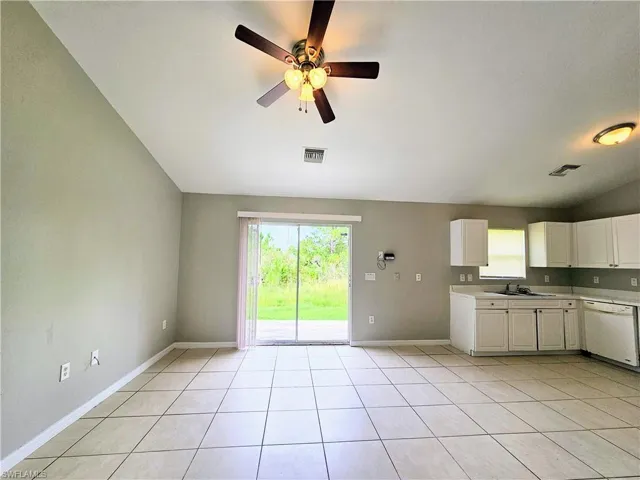 Kitchen featuring lofted ceiling, white cabinetry, dishwasher, light tile patterned floors, and ceiling fan