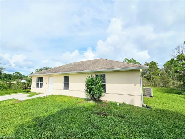 View of side of home featuring a lawn and stucco siding