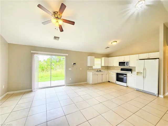 Kitchen with white appliances, white cabinetry, light countertops, lofted ceiling, and light tile patterned flooring